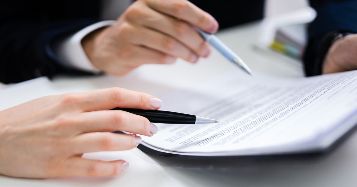 two people with pens looking at paperwork