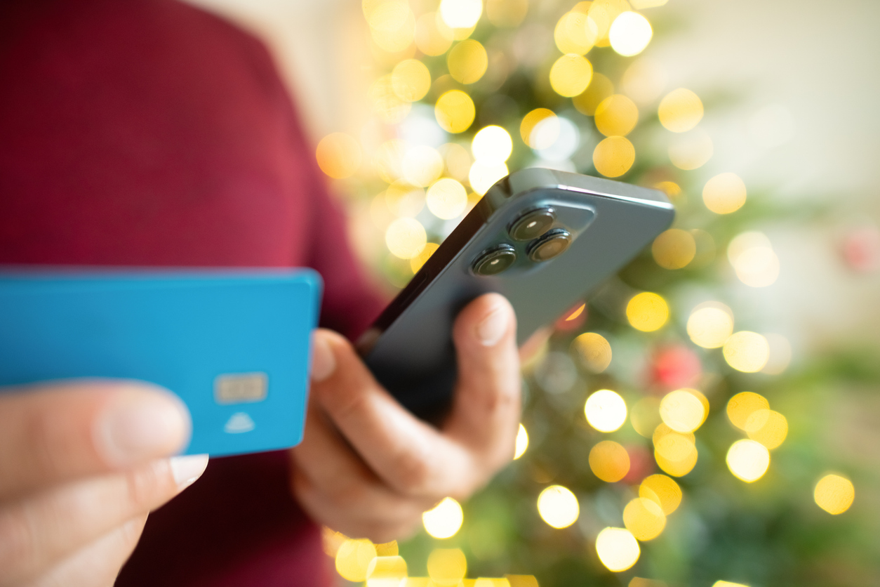 A person in a red shirt holding a blue credit card and a smart phone.